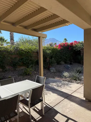 a view of a patio with a table chairs and a small yard