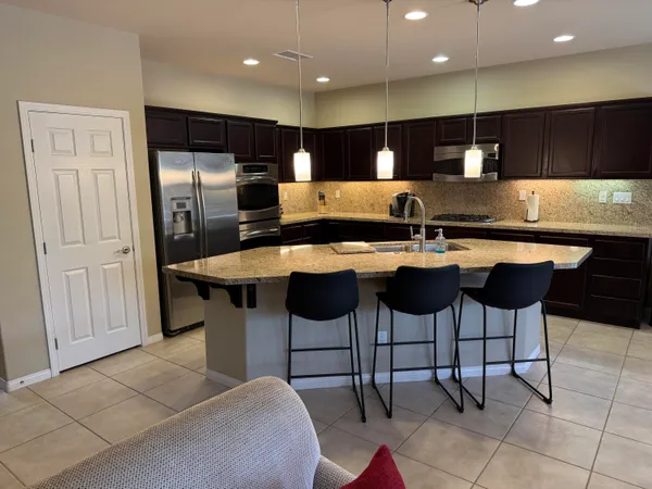 a kitchen with stainless steel appliances kitchen island granite countertop a table and chairs in it