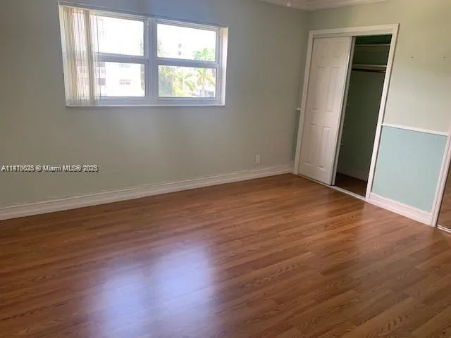 a view of a hallway with wooden floor and closet
