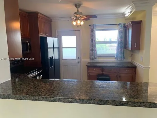a kitchen with kitchen island granite countertop a sink a counter top space and cabinets