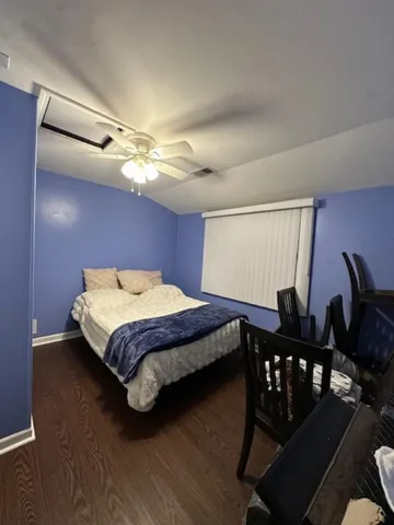 a bedroom with a bed and dresser with wooden floor