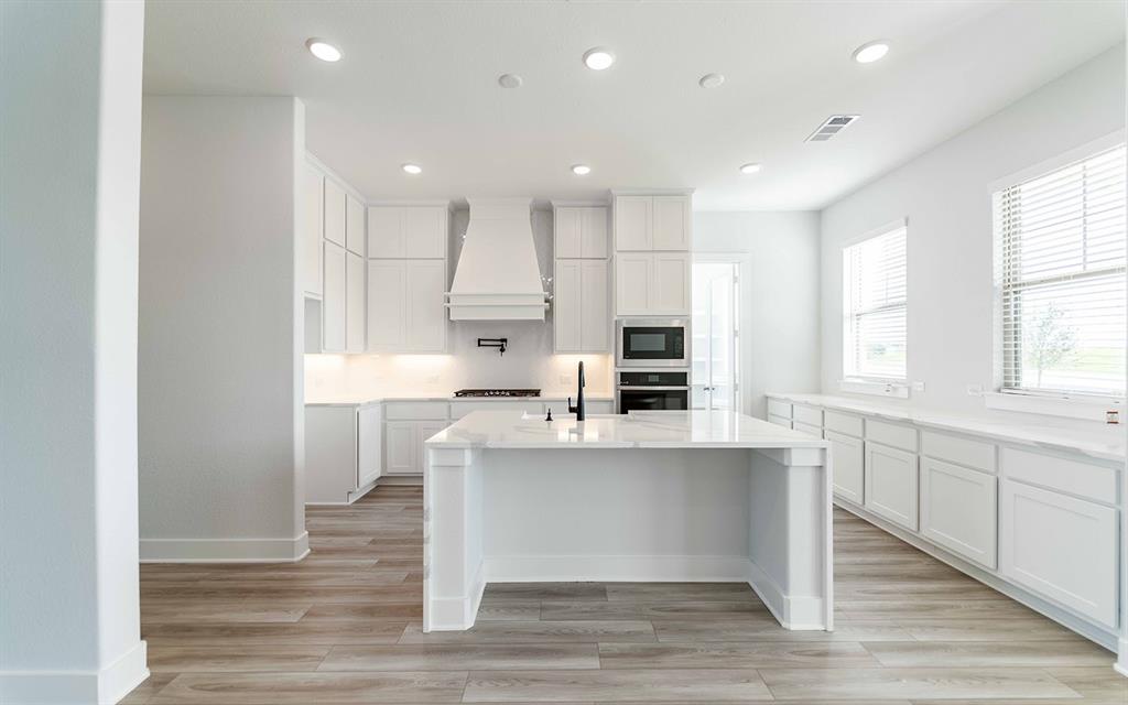 2012 Casting Ridge Mesquite, TX 75181 - Photo 8 of 28 a large white kitchen with kitchen island a sink a stove a refrigerator and white cabinets with wooden floor