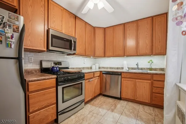 a kitchen with stainless steel appliances granite countertop a stove top oven a sink dishwasher and a microwave oven with white cabinets