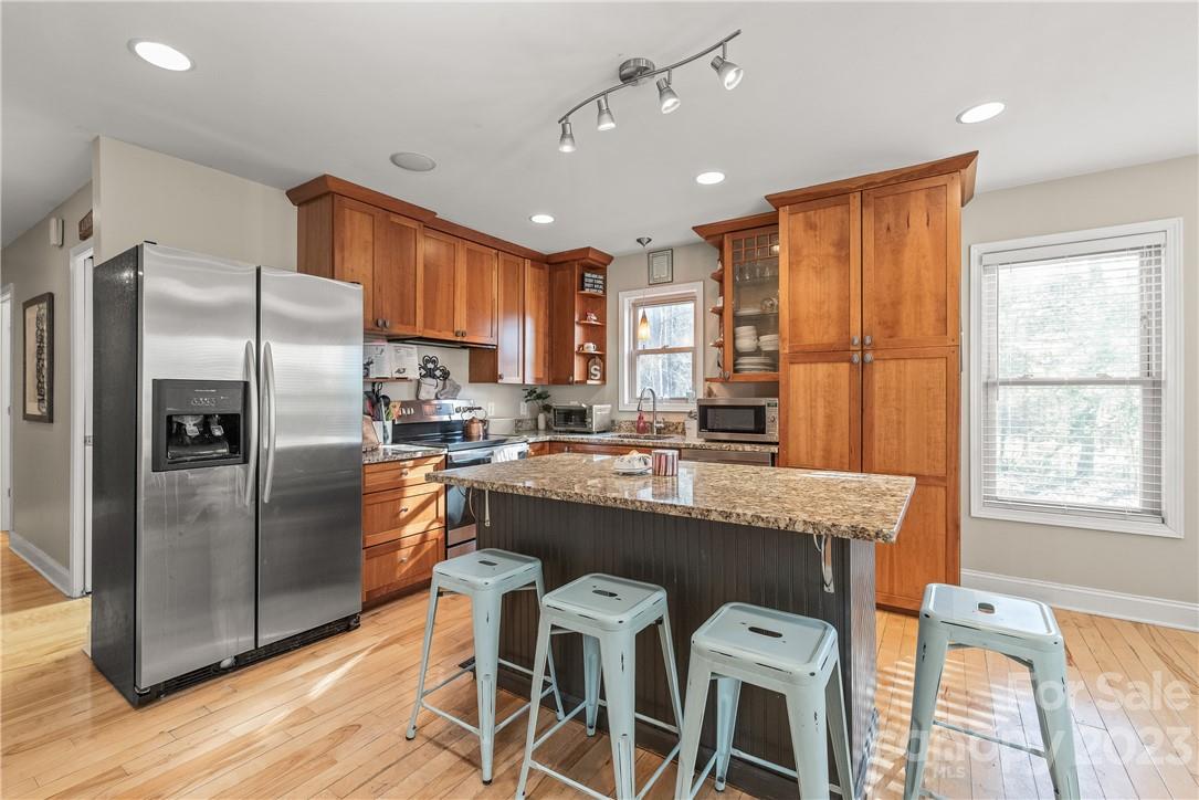 13801 East Rocky River Road Davidson, NC 28036 - Photo 20 of 42 a kitchen with stainless steel appliances granite countertop a refrigerator a sink dishwasher a stove and a dining table with wooden floor
