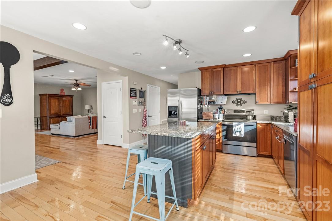 13801 East Rocky River Road Davidson, NC 28036 - Photo 22 of 42 a kitchen with stainless steel appliances kitchen island granite countertop a refrigerator a stove a sink and a dining table with wooden floor