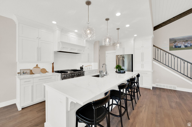 352 East Boulderville Road Oakley, UT 84055 - Photo 12 of 62 Kitchen featuring a kitchen bar, an island with sink, white cabinets, dark wood finished floors, and stainless steel appliances