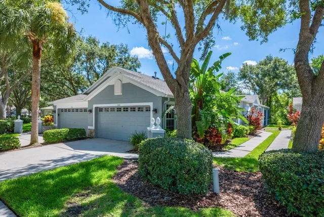 a view of a house with a yard and large trees
