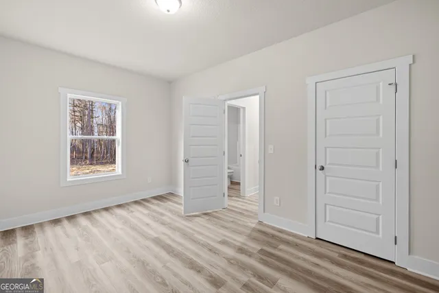 an empty room with wooden floor closet and windows