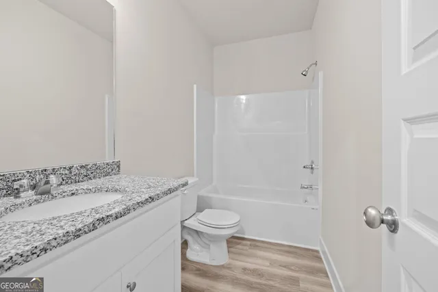 a bathroom with a granite countertop sink a toilet and shower