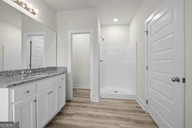 a bathroom with a granite countertop sink a mirror and a shower