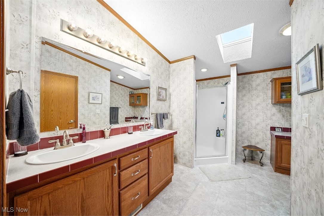 17296 Old State Road Middlefield, OH 44062 - Photo 18 of 44 Bathroom with vanity, a shower with door, crown molding, vaulted ceiling with skylight, and a textured ceiling