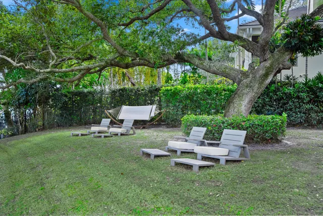a white bench sitting in the grass near a tree