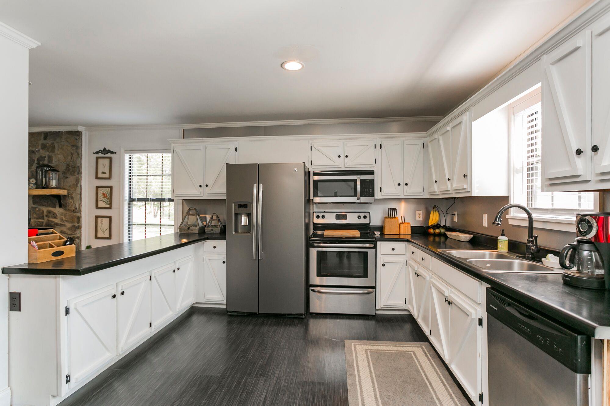 7690 Joe Rowlin Road Christiana, TN 37037 - Photo 11 of 18 a kitchen with stainless steel appliances granite countertop white cabinets a sink a stove a refrigerator and microwave with wooden floor