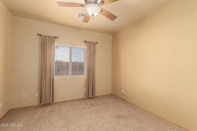 an empty room with chandelier fan and stainless steel appliances