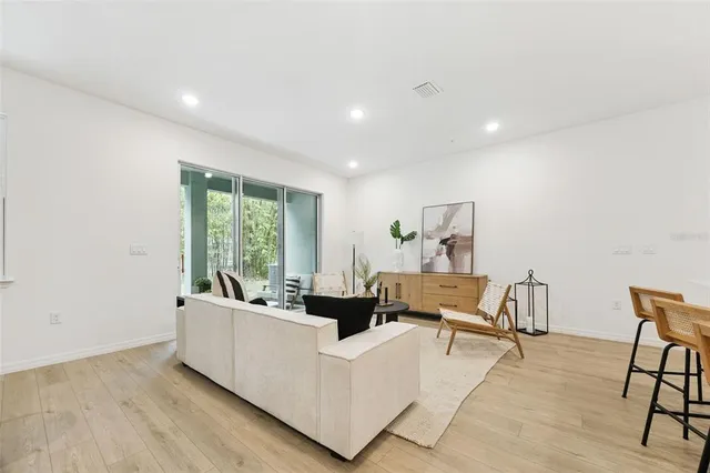 a living room with stainless steel appliances furniture and a kitchen view