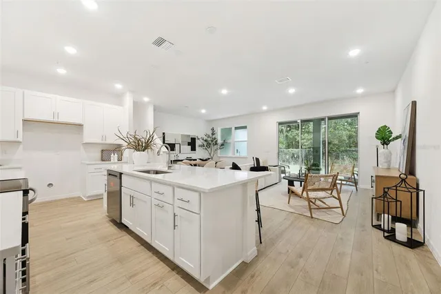 a dining hall with stainless steel appliances granite countertop a table chairs and a refrigerator