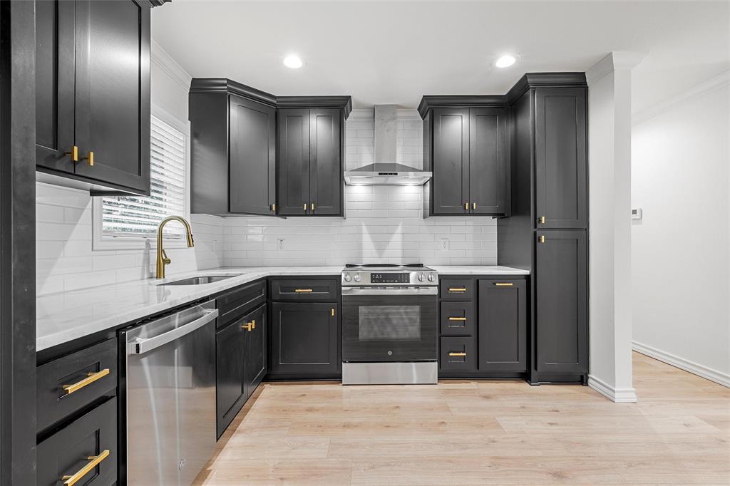 611 North Rita Street Lacy-Lakeview, TX 76705 - Photo 4 of 17 Kitchen with light stone countertops, stainless steel appliances, wall chimney exhaust hood, backsplash, and light wood finished floors