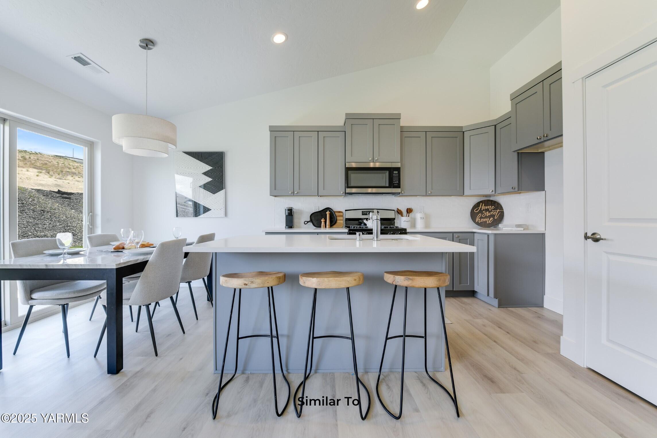 506 Grapevine Street, Unit PHASE 3 LOT 11) SPEC Grandview, WA 98930 - Photo 7 of 22 a kitchen with stainless steel appliances a table chairs refrigerator and microwave