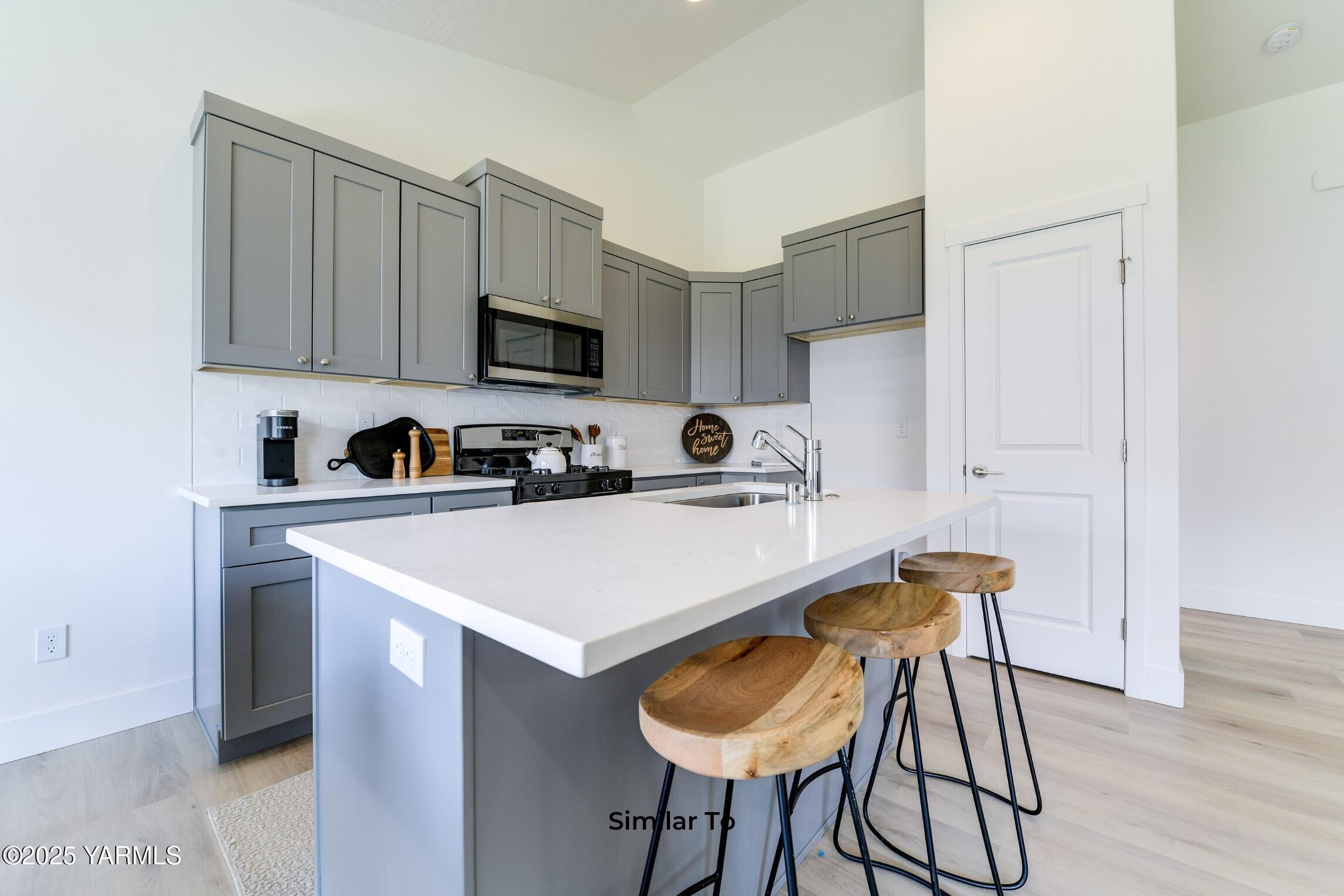 506 Grapevine Street, Unit PHASE 3 LOT 11) SPEC Grandview, WA 98930 - Photo 8 of 22 a kitchen with stainless steel appliances a sink a stove a refrigerator cabinets and a dining table