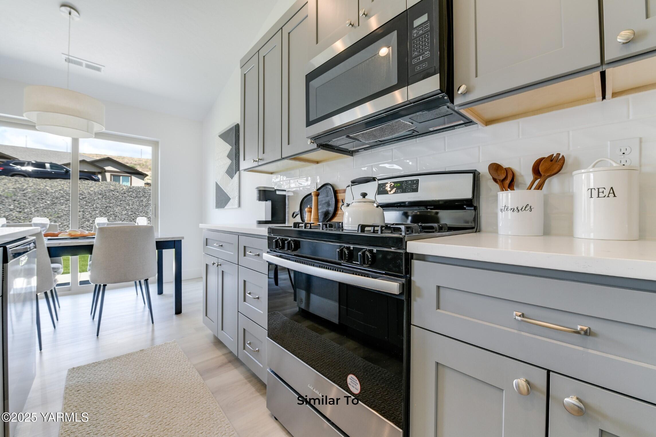 506 Grapevine Street, Unit PHASE 3 LOT 11) SPEC Grandview, WA 98930 - Photo 9 of 22 a kitchen with stainless steel appliances granite countertop a stove a sink and a microwave