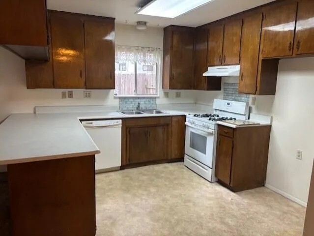 a kitchen with stainless steel appliances a sink a stove a refrigerator and cabinets