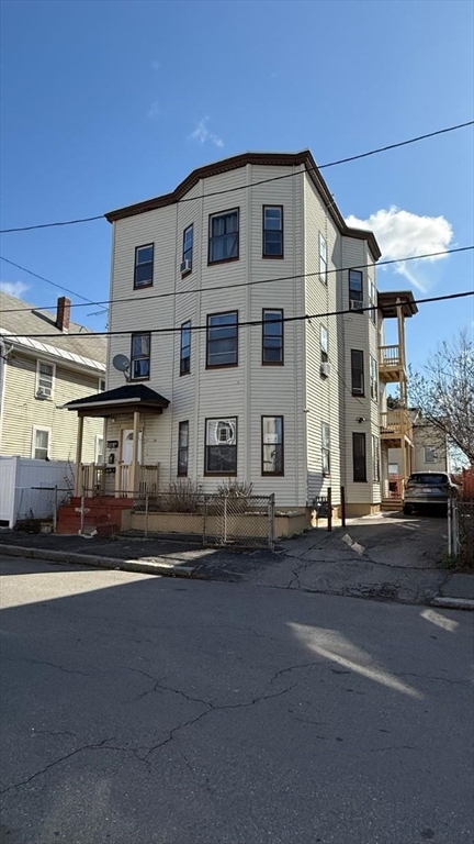 13 Walnut Street Lawrence, MA 01841 - Photo 1 of 3 a front view of a building with lot of cars and trees