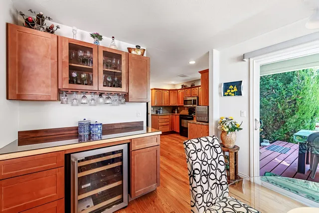 a kitchen with stainless steel appliances granite countertop a stove top oven a sink dishwasher a dining table and chairs with wooden floor