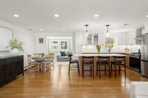 a dining room with stainless steel appliances furniture large wooden floor and a kitchen view