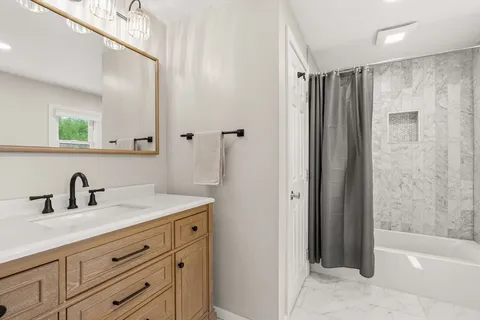 a bathroom with a shower sink vanity and mirror