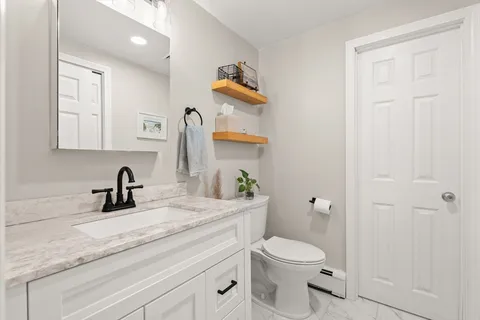 a bathroom with a toilet sink vanity and mirror