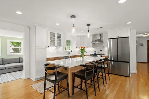 a kitchen with stainless steel appliances kitchen island granite countertop a dining table chairs refrigerator and sink