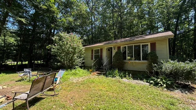 a view of house with yard and sitting area