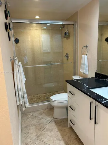 a bathroom with a granite countertop sink toilet and shower