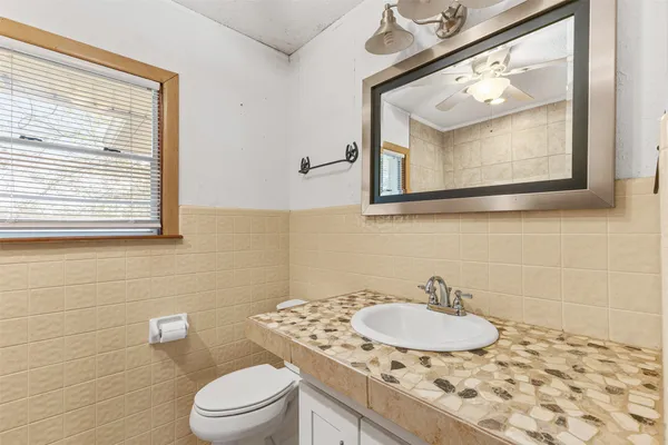 a bathroom with a toilet a sink a mirror and a window