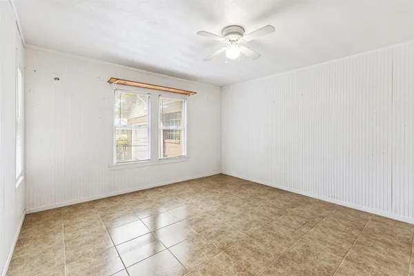 an empty room with windows and chandelier fan