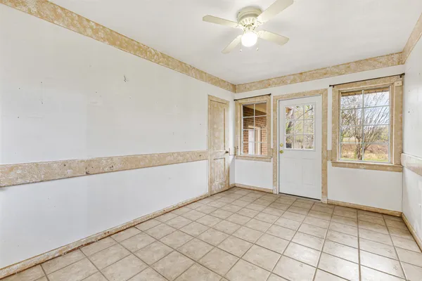 a view of an empty room with window and chandelier fan