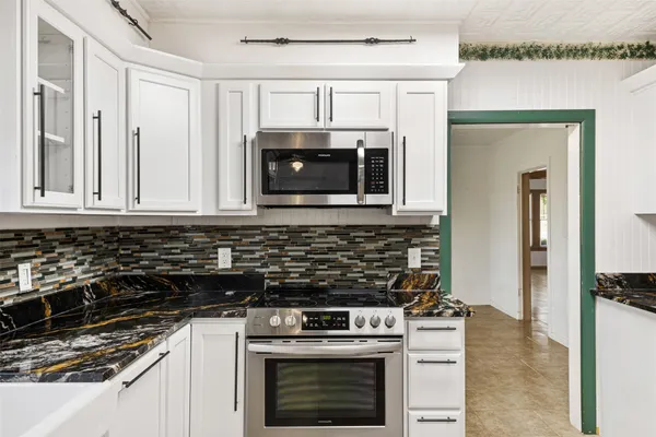 a kitchen with granite countertop white cabinets and stainless steel appliances