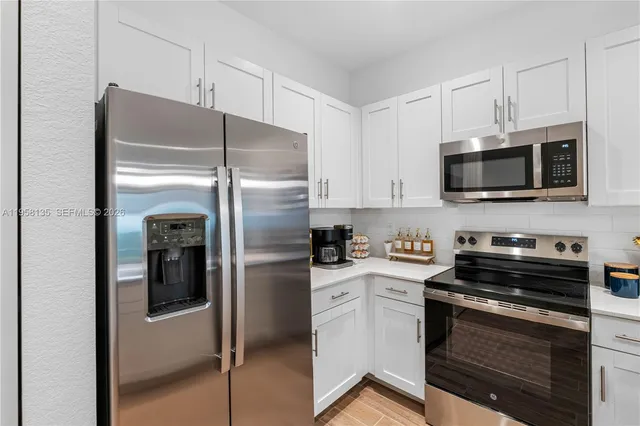 a kitchen with stainless steel appliances white cabinets and a refrigerator