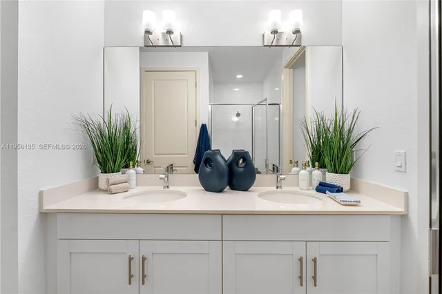 a bathroom with a sink a potted plant and a mirror
