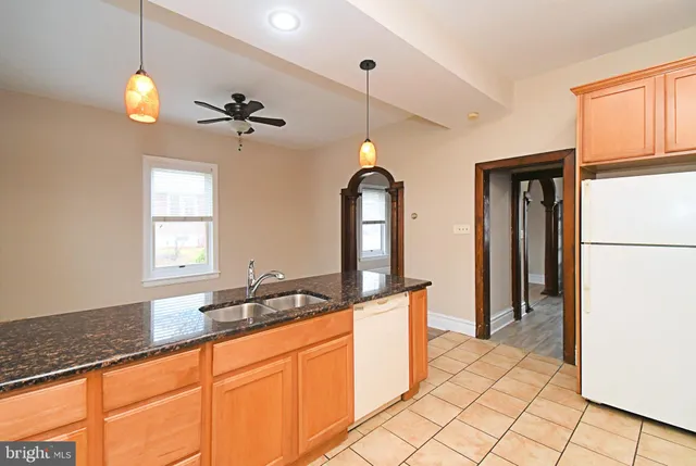 a kitchen with stainless steel appliances granite countertop a refrigerator a sink and white cabinets