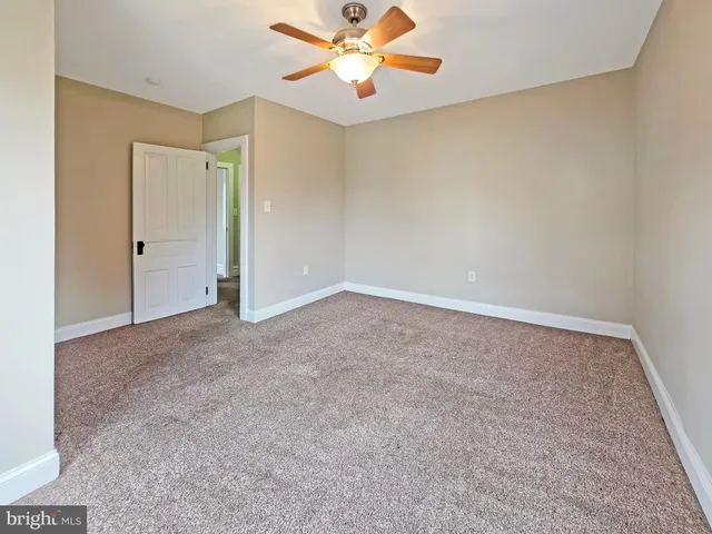 an empty room with windows and chandelier fan