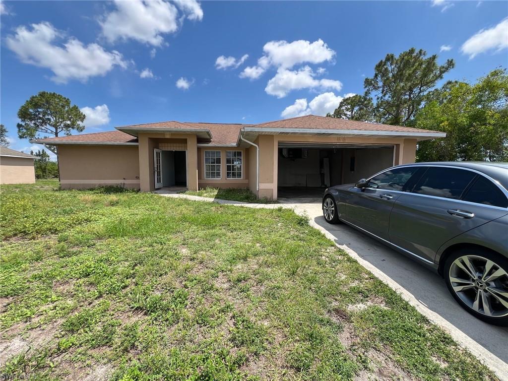3513 30th Street Southwest Lehigh Acres, FL 33976 - Photo 2 of 29 a view of a house with a big yard and potted plants