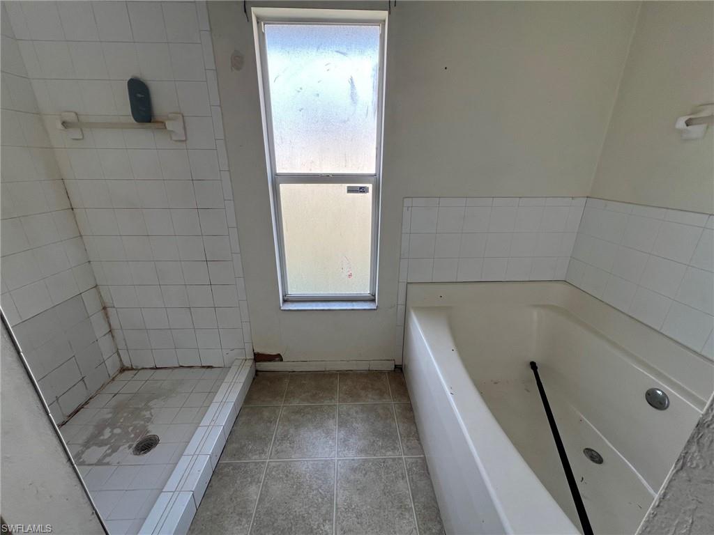 3513 30th Street Southwest Lehigh Acres, FL 33976 - Photo 22 of 29 a bathroom with a tub a window and a shower