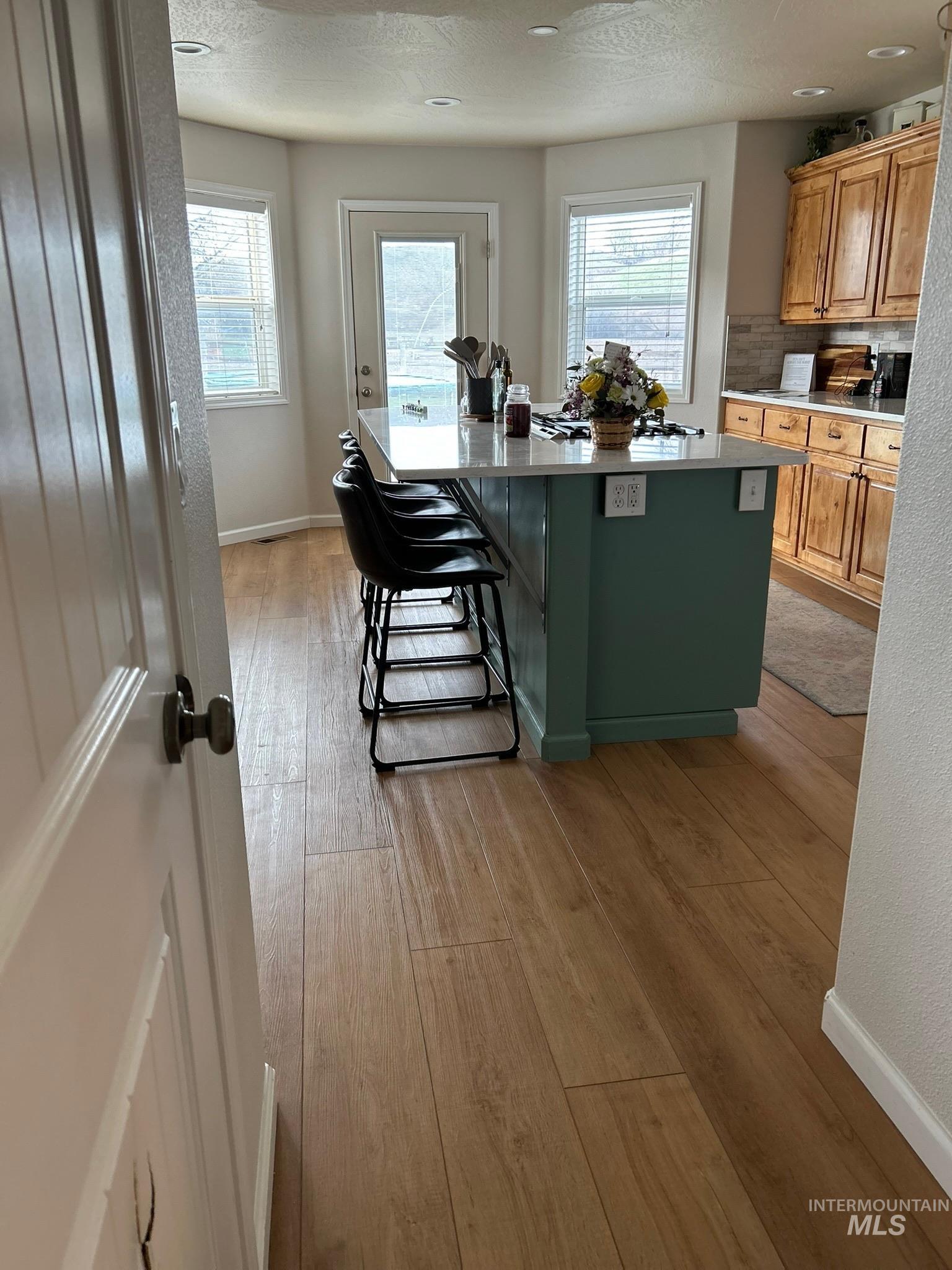 3091 Echo Road Nyssa, OR 97913 - Photo 19 of 36 Kitchen with light wood-style floors, a breakfast bar, a kitchen island, green cabinetry, and plenty of natural light