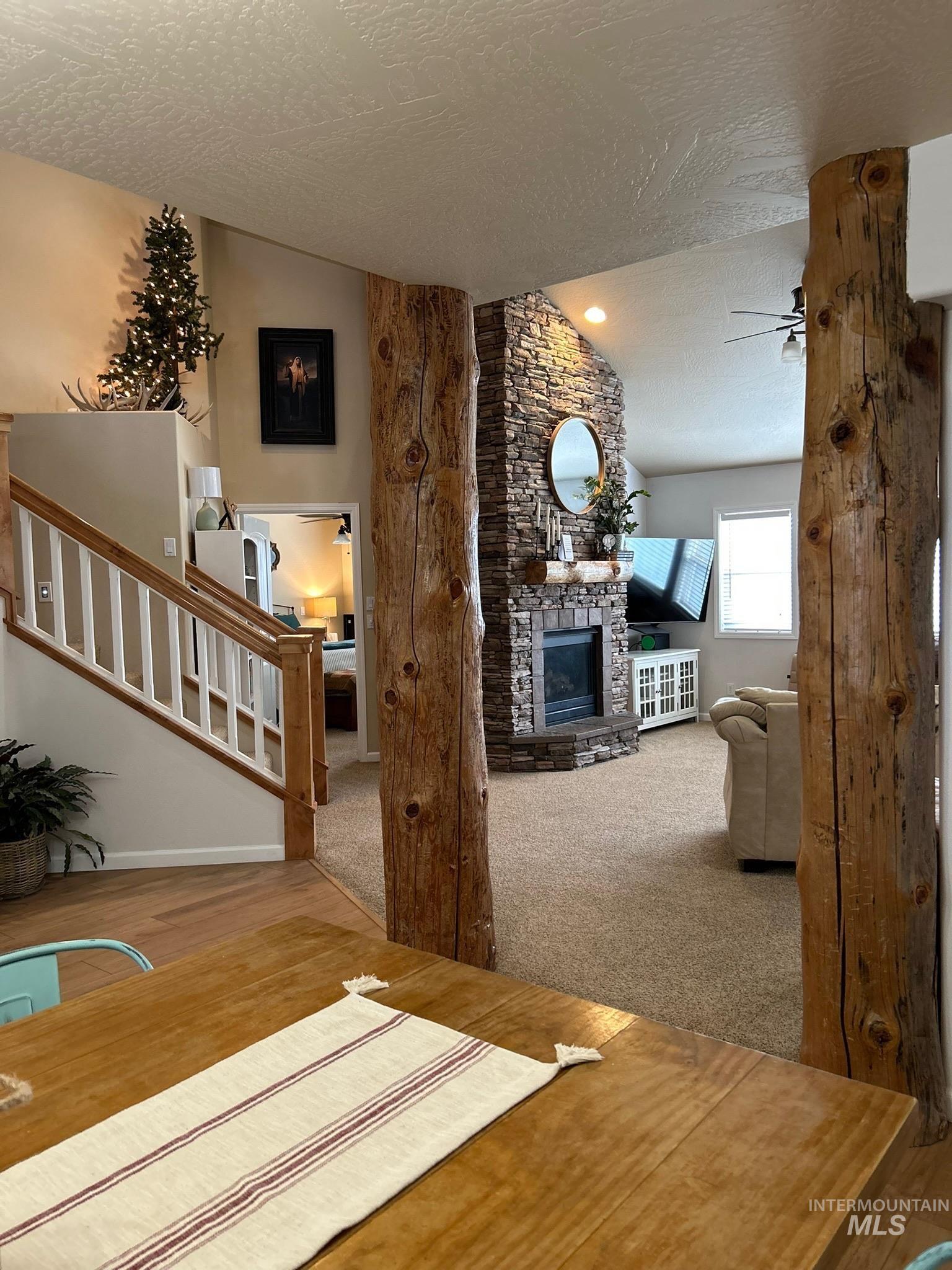 3091 Echo Road Nyssa, OR 97913 - Photo 21 of 36 Carpeted living area with a textured ceiling, vaulted ceiling, a fireplace, stairway, and a ceiling fan