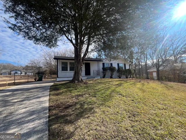 a view of a house with a yard and large tree