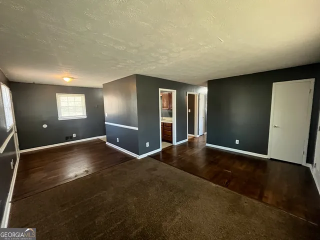 a view of an empty room with window and wooden floor