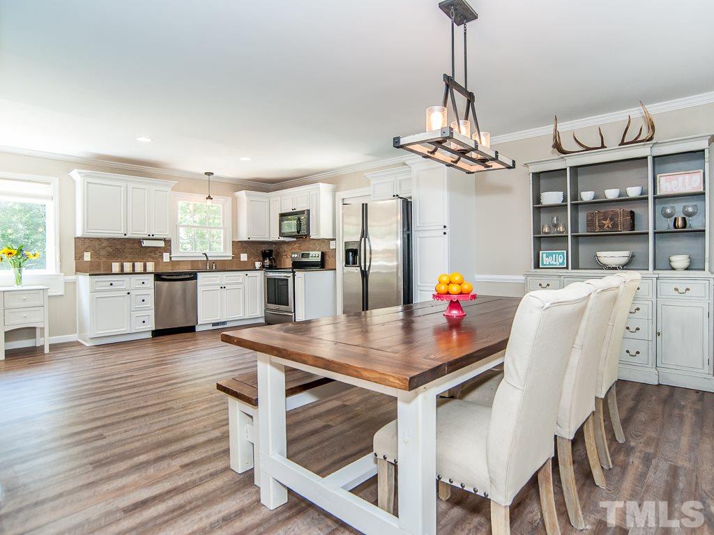 7605 Elliot Drive Raleigh, NC 27613 - Photo 1 of 22 a kitchen with stainless steel appliances kitchen island granite countertop a dining table chairs and refrigerator