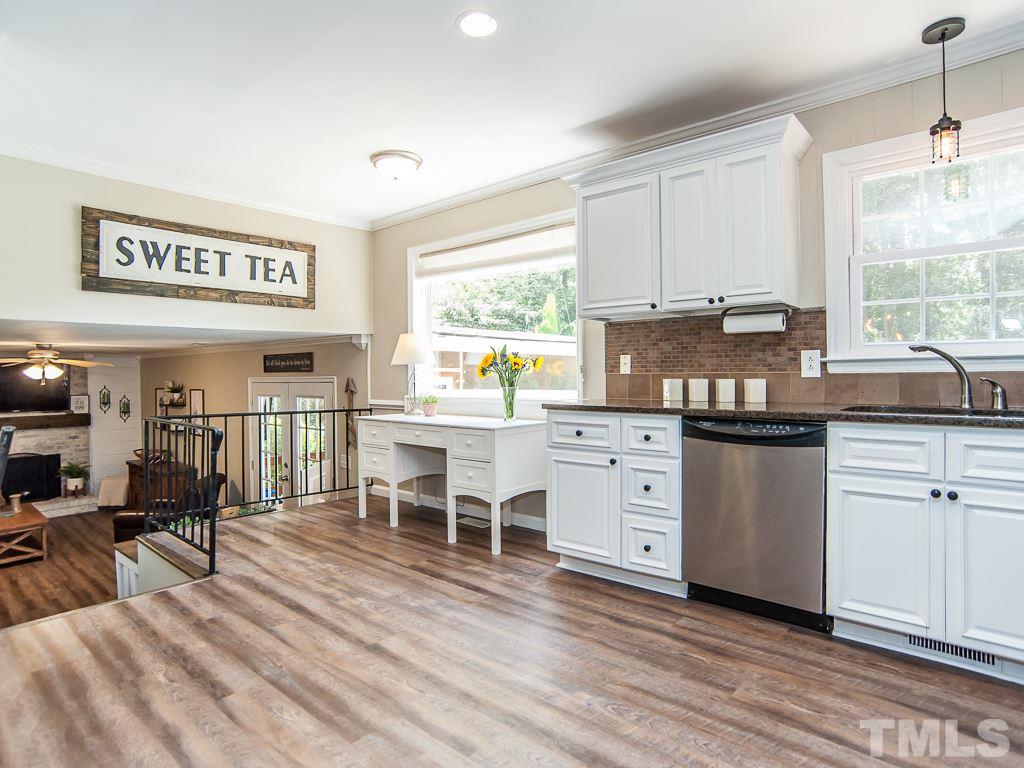 7605 Elliot Drive Raleigh, NC 27613 - Photo 3 of 22 a kitchen with stainless steel appliances granite countertop a stove a sink dishwasher and white cabinets with wooden floor