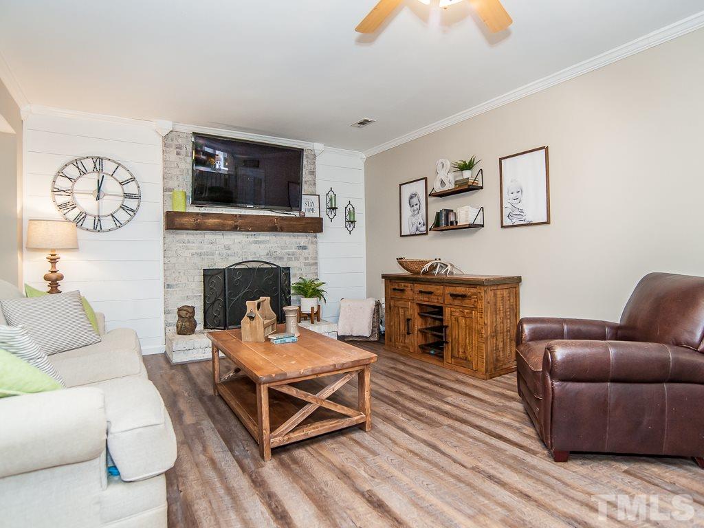 7605 Elliot Drive Raleigh, NC 27613 - Photo 6 of 22 a living room with furniture a flat screen tv and a fireplace
